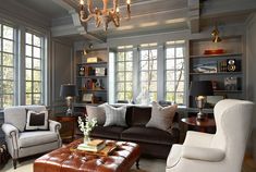 a living room filled with lots of furniture and windows covered in chandelier hanging from the ceiling