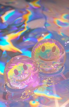 two smiley faces floating on top of water with colorful bubbles in the backround