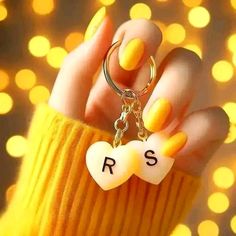 a hand holding a keychain with the word rs on it and a heart