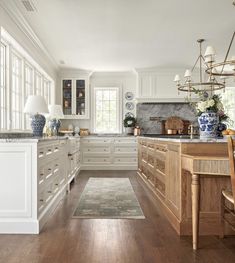 a large kitchen with wooden floors and white cabinets, along with an area rug on the floor