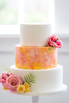 a three tiered cake with flowers on top