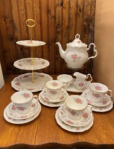 a wooden table topped with lots of white dishes and tea cups filled with saucers