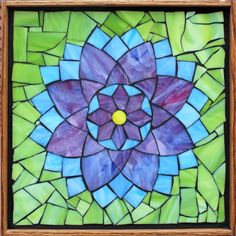 a stained glass window with a flower in the center and blue, green, purple, and yellow colors