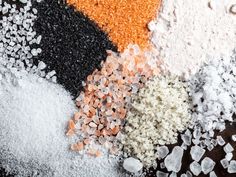 several different types of salt and pepper on top of each other, including black, white, and orange