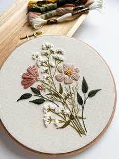 a close up of a embroidery on a wooden hoop with some flowers in the middle