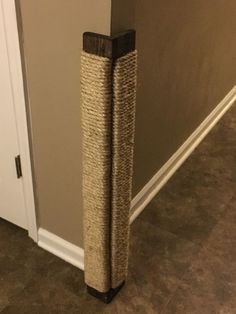 a close up of a cat scratching post on the ground near a door and carpeted floor