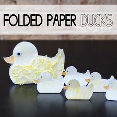 some paper ducks sitting on top of a table next to each other and the words folded paper ducks above them