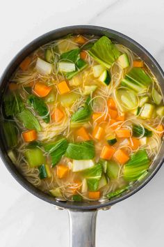 a pot filled with noodles and vegetables on top of a table