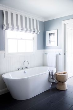 a large white bath tub sitting next to a toilet in a bathroom under a window