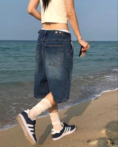 a woman standing on the beach with her legs crossed