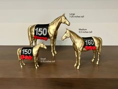 three gold horses with numbers on them and roses in their manes, standing next to each other