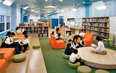 children are sitting in the library with bookshelves full of books and reading materials