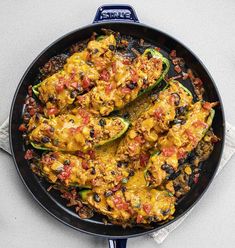 a skillet filled with mexican food on top of a white countertop next to a napkin