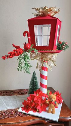 a red birdhouse decorated with poinsettis and christmas decorations on a table