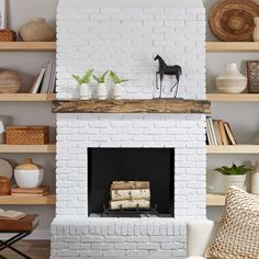 a white brick fireplace in a living room with wooden shelves and candles on the mantle