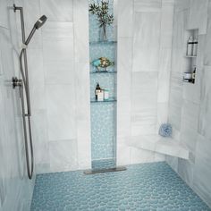 a bathroom with blue and white tiles on the floor, shower stall and shelves in the wall