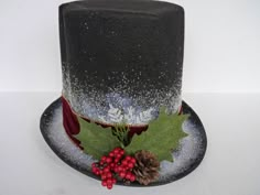 a black top hat with holly berries and pine cones