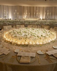 a round table with candles and flowers on it is set for a formal dinner or reception