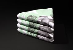 four folded napkins on top of each other in green and white designs with black background