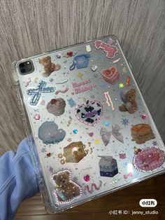 someone is holding up a clear case with many different things on it, including teddy bears and hearts