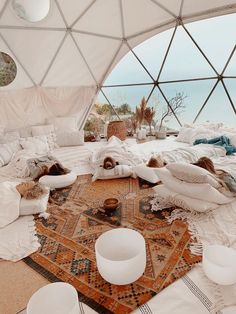 there are many pillows and blankets on the floor in this dome room that looks out onto the ocean