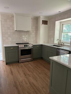 an empty kitchen with wood flooring and green cabinets on either side of the stove