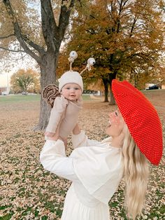 a woman holding a baby in her arms and wearing a red hat on top of her head