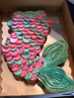 a decorated cake in the shape of a mermaid tail with pink, green and blue icing