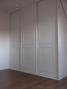 an empty room with white walls and wood flooring is pictured in this image, there are three doors on each side of the wall