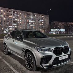 the new bmw x4 suv is parked in an empty parking lot at night time