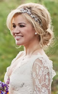 a woman in a wedding dress holding a bouquet of flowers and smiling at the camera