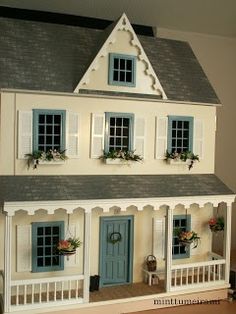 a doll house with blue shutters and white trim on the front door, windows and porch