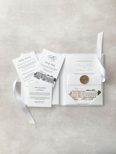 an open pocketfold wedding card with a gold coin on top and white ribbon around it