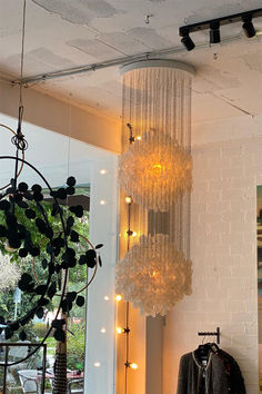 a chandelier hanging from the ceiling in front of a window with lights on it