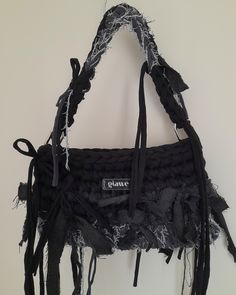 a black purse hanging on a wall with fringes and lace around the bottom part