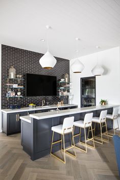 a large kitchen with an island and bar stools in front of the tv on the wall