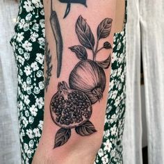 a woman with a tattoo on her arm has a pomegranate and leaves