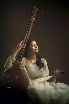 a woman in white dress holding an instrument