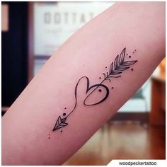 a tattoo on the arm of a woman with an arrow and heart in the middle