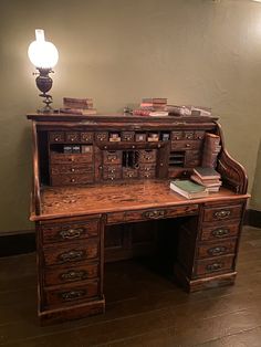 an old wooden desk with lots of books on it and a lamp next to it