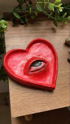 a red heart shaped object sitting on top of a wooden table