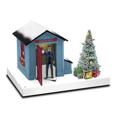 a small christmas tree is in front of a blue building with a man standing at the door