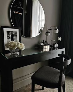 a desk with a mirror, chair and flowers on it