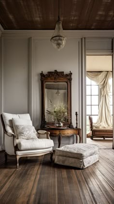 a chair and ottoman in a room with wood flooring on one side and an antique mirror on the other