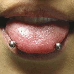 a woman's tongue with two balls attached to the top of her lip,