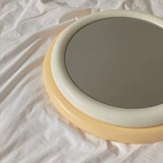 a round mirror sitting on top of a white sheet