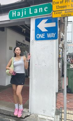 a woman standing next to a one way sign