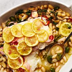 a white bowl filled with fish, beans and lemon slices