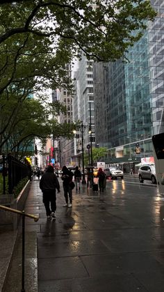 people are walking down the sidewalk on a rainy day