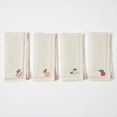 three pieces of cloth with embroidered fruit designs on them, lined up next to each other